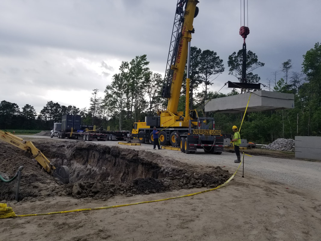 Picture of a large crane moving a septic tank into place.